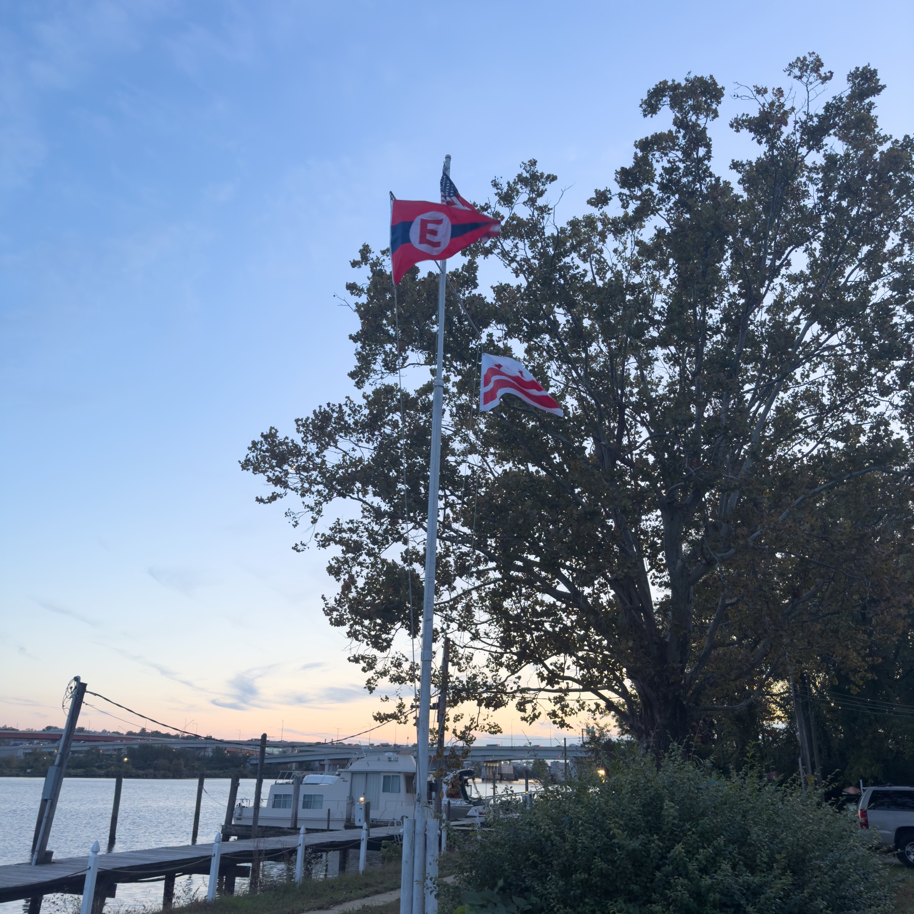 The club burgee and ensign flying at dusk over the river