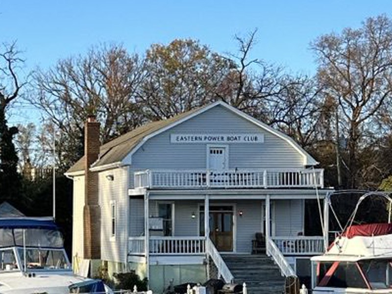 The Eastern Power Boat Club clubhouse today, lettered with the club’s name above its double porch, boats docked on the Anacostia in front.