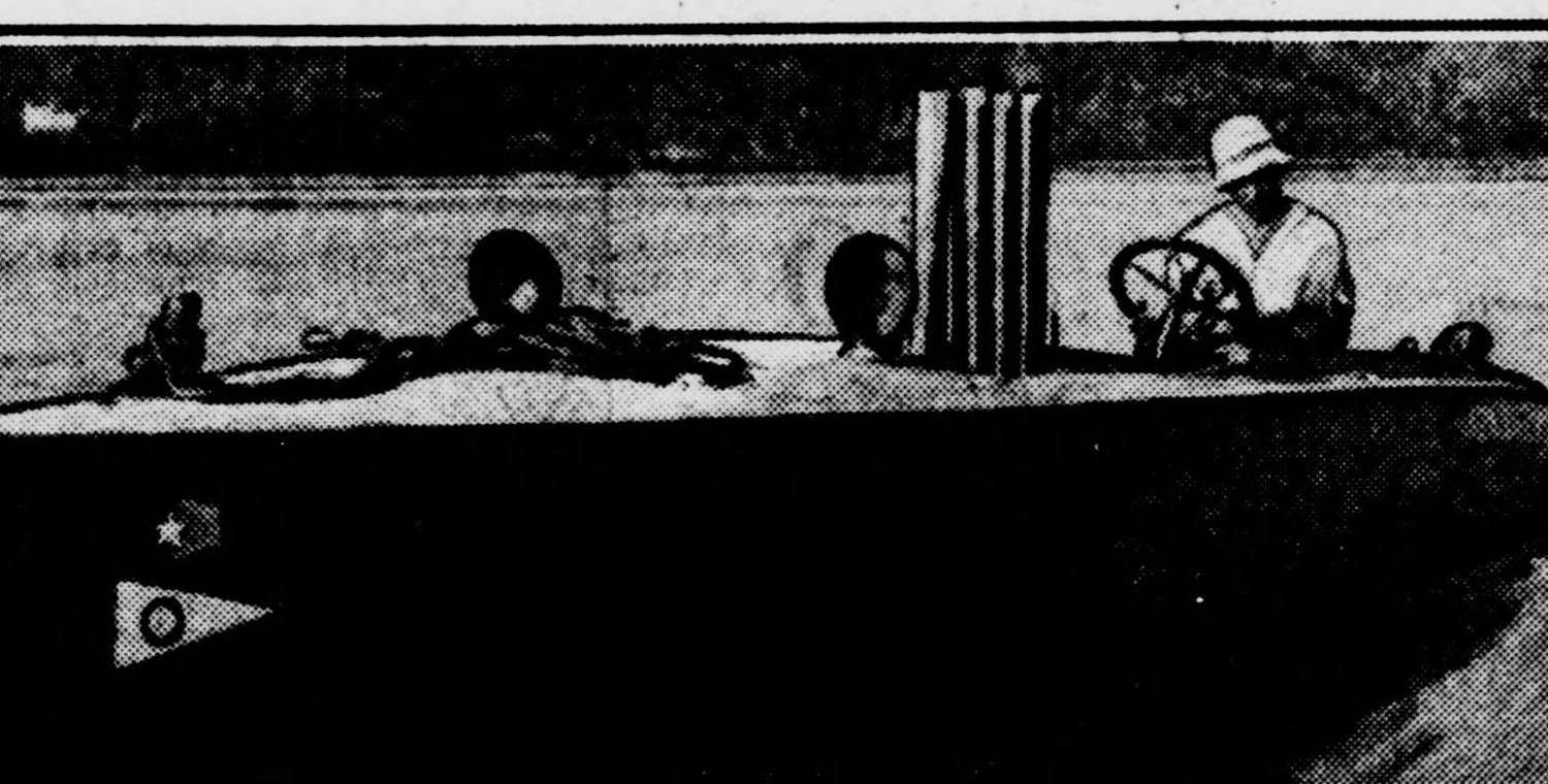 Commodore Battenfield at the wheel of his racing boat the Gray Bat, a Corinthian Yacht Club burgee on the bow.