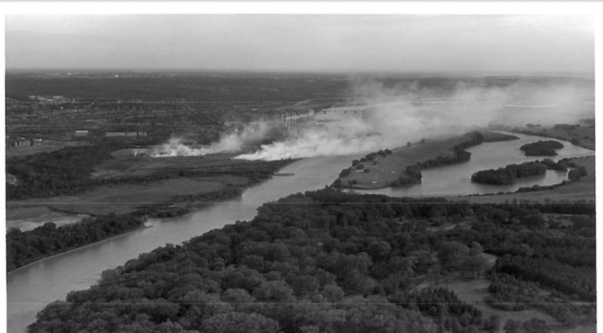 An aerial view of the Anacostia River with smoke rising from the burning Kenilworth dump on the bank.