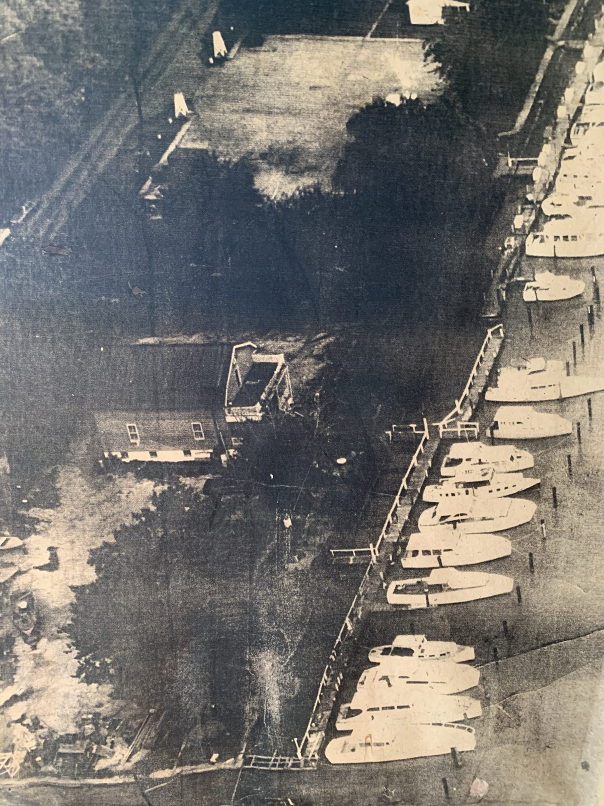 An aerial print from the club archives: the clubhouse and a full line of boats at the dock