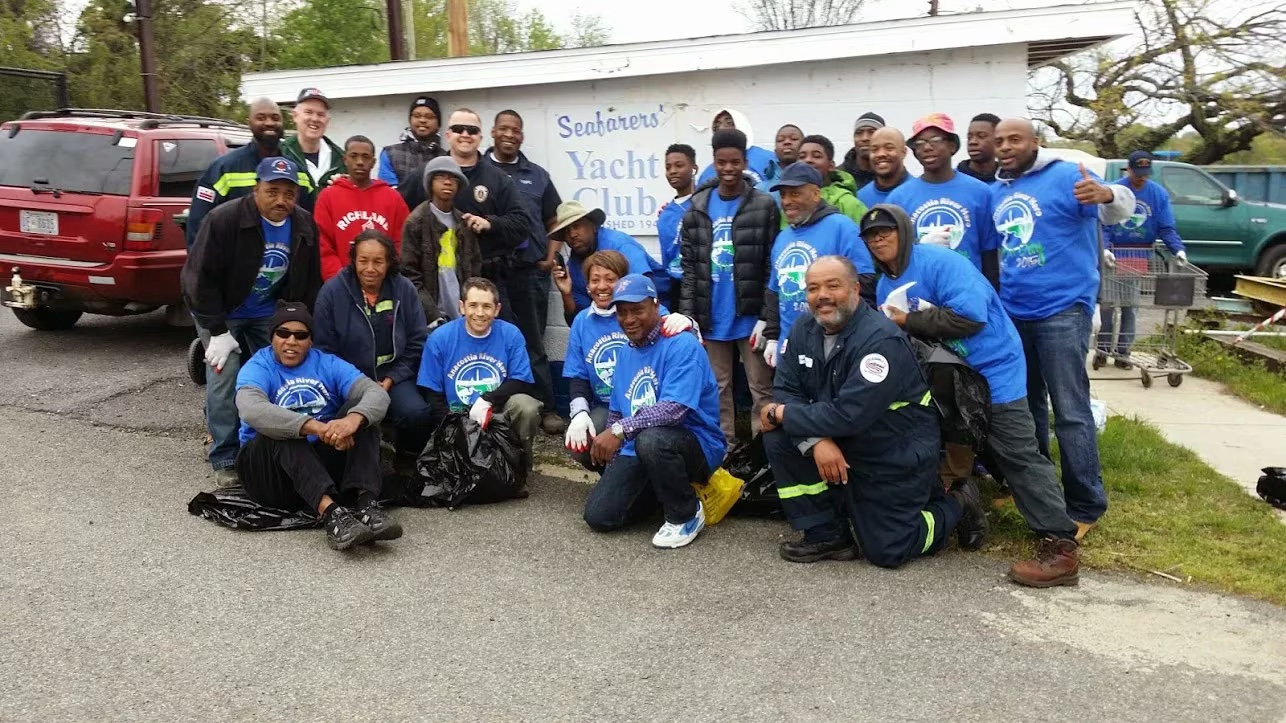 A large group of Anacostia River cleanup volunteers in blue shirts gathered outside the Seafarers Yacht Club.